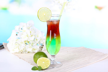 Glass of cocktail on table on light blue background