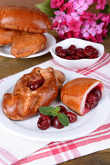 Fresh baked pasties with cherry on plate on table close-up