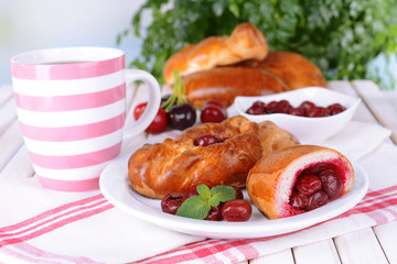 Fresh baked pasties with cherry on plate on table close-up