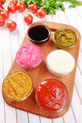 Various sauces on chopping board on table close-up