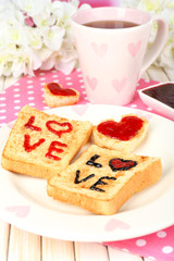 Delicious toast with jam and cup of tea on table close-up