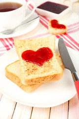 Delicious toast with jam and cup of tea on table close-up