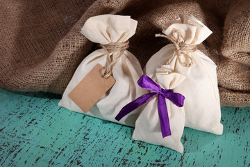 Sacks on color wooden table, on sackcloth background
