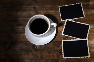 Coffee cup and old blank photos, on wooden background
