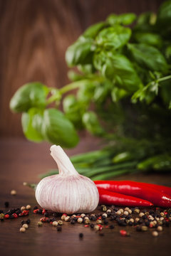 Garlic with pepper and green herbs on wood