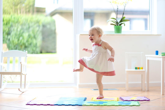 Happy blonde toddler girl having fun dancing indoors 