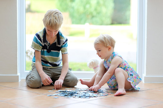 toddler girl playing puzzles with her teenager brother