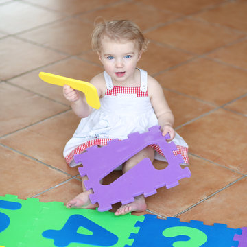 Happy toddler girl playing with colorful numbers puzzles