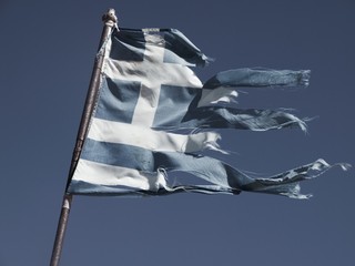 Old and torn flag of Greece on dark blue sky