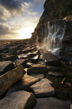 Beautiful landscape image waterfall flowing into rocks on beach