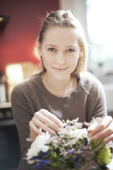 portrait of a beautiful young woman arranging a bouquet of flowe