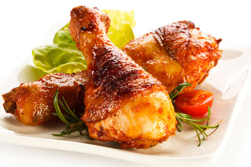 Grilled chicken legs and vegetables on white background