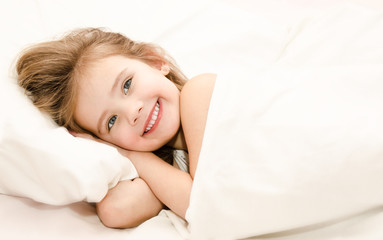 Fototapeta na wymiar Adorable little girl waked up in her bed