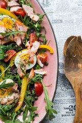 salad with salmon and verdure in pink plate on retro newspaper b