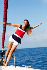 Happy woman on the bow of a Sail Boat with arm raised. Copy space