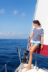 Beautiful young woman standing on the bow of a Sailboat, looking away. Copy space