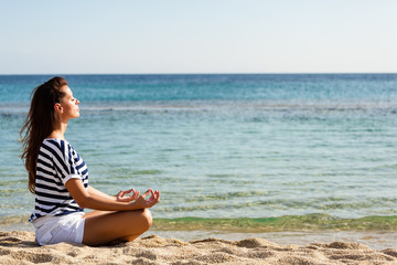 Fototapeta na wymiar Beautiful woman meditating at the beach.Copy space