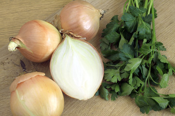 Onions and green parsley on brown kitchen desk closeup