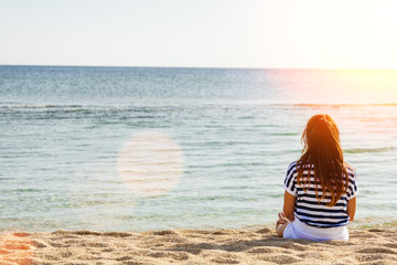 Rear view of woman enjoys a sunny day relaxing on the beach.Copy space,lens flare