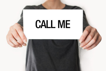 Call me. Female in black shirt showing or holding a card