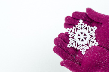 Close up on hands wearing pink gloves holding a big snowflake. 