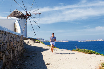 Happy woman running along a coastline near to the windmill.Copy space