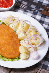 Schnitzel with young boiled potatoes on a white plate closeup