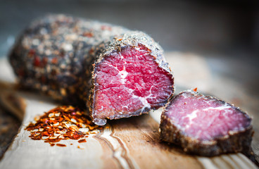 Dried meat with pepper and salt on rustic wooden background