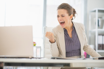 Happy business woman in office rejoicing success