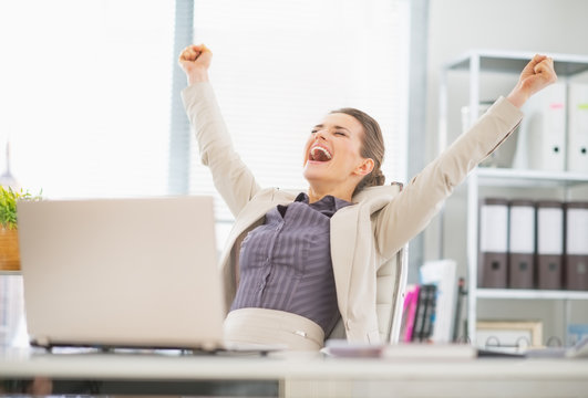 Portrait of happy business woman in office rejoicing success