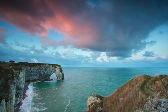 pink stormy sunrise over cliffs in ocean