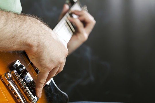 Close up on man`s hand playing guitar