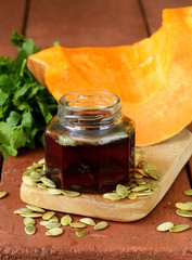 organic pumpkin oil in a glass jar on a wooden table