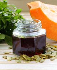 organic pumpkin oil in a glass jar on a wooden table