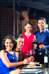 Asian Friends toasting with wine in restaurant
