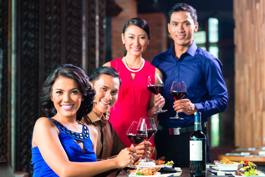 Asian Friends toasting with wine in restaurant