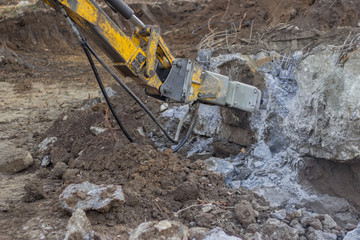 Excavator with hydraulic hammer breaking concrete 2
