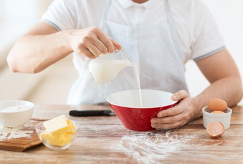 close up of male hand pouring milk in bowl