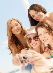 smiling girls taking photo in cafe on the beach