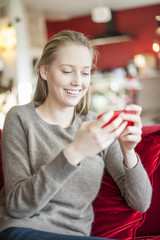 cheerful young woman sending a message on her smartphone sit on