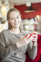 cheerful young woman sending a message on her smartphone sit on