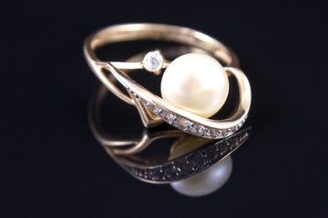 gold ring with a pearl is reflected from the floor