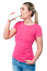 Young woman drinking tumbler of coffee