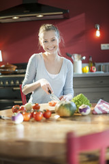 beautiful young woman slicing tomatoes on her kitchen's table