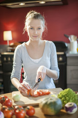 beautiful young woman slicing tomatoes on her kitchen's table