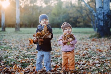 brother and sister playing in autumn park leaves