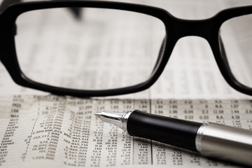 closeup glasses on financial newspaper