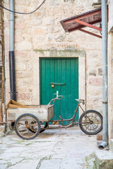 Fototapeta na wymiar Three Wheeled Bike with Cart by Green Door