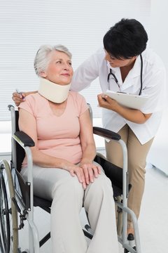 Doctor talking to senior patient in wheelchair with cervical