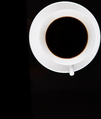Coffee in a white cup over black background